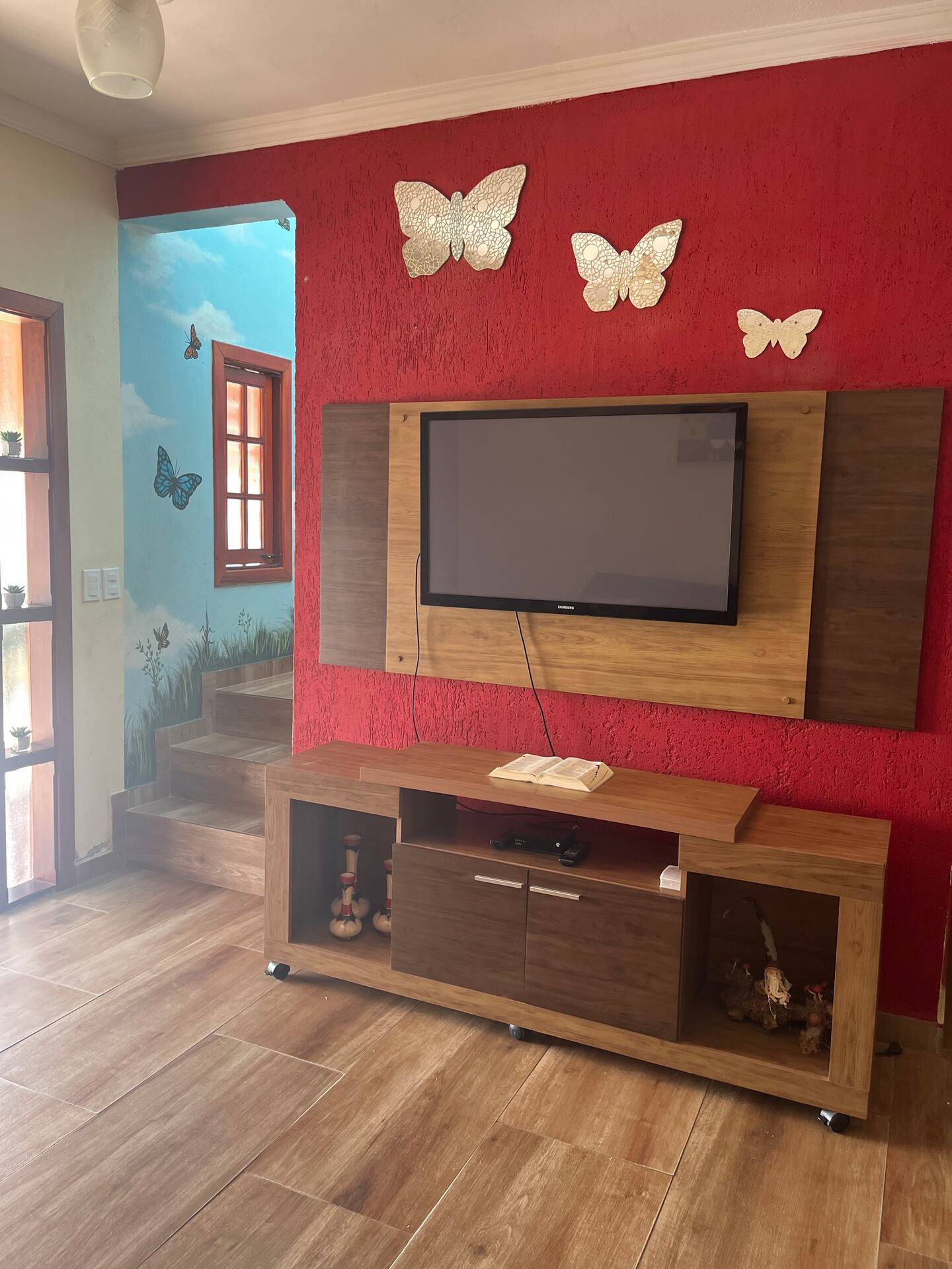 Sala da casa grande com painel de televisão e decoração de borboletas.